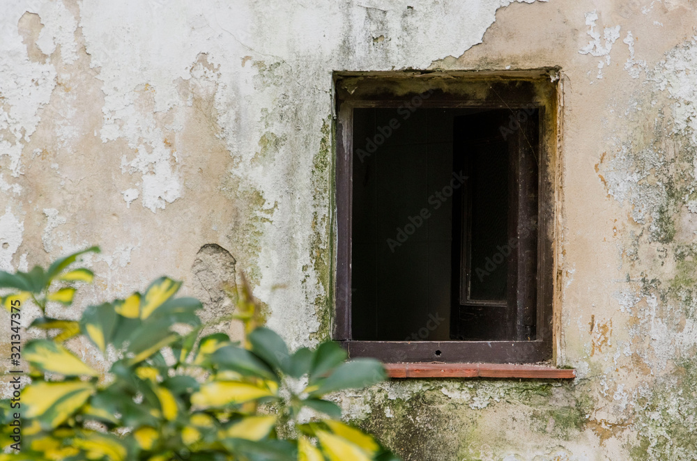 Old open window in a wall with worn paint