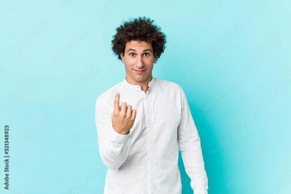 Young curly mature man wearing an elegant shirt pointing with finger at you as if inviting come closer. Young curly mature man wearing an elegant shirt pointing with finger at you as if inviting come closer.