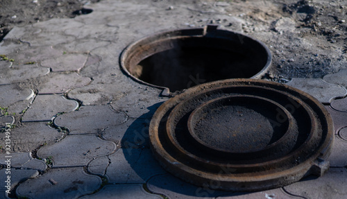 An open hatch with a lid nearby is located on the street