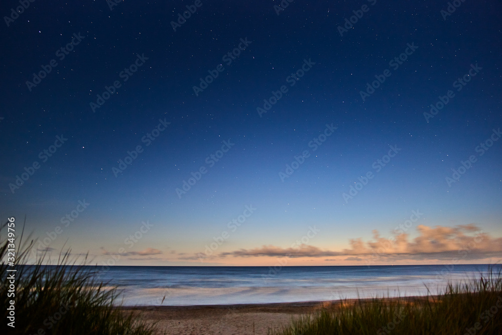 Incredible sunset on the beach coast against the background of the starry sky.