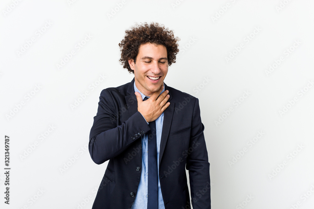 Young business curly man against white background laughs out loudly keeping hand on chest. Young business curly man against white background laughs out loudly keeping hand on chest.