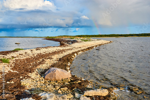 Beautiful sunset with a rainbow on the coast of the sea with a rocky shore photo