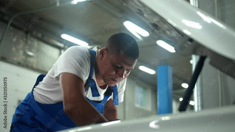 Mechanic in uniform repair the motor of car Mechanic in uniform repair the motor of car