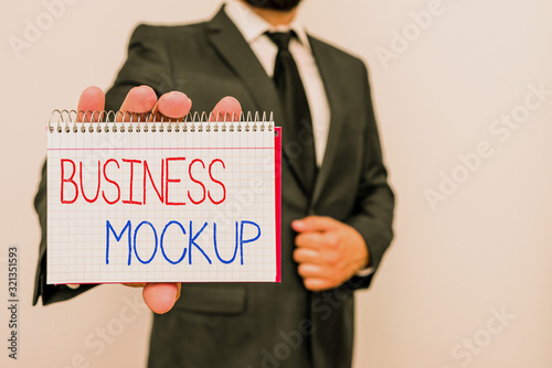 Conceptual hand writing showing Business Mockup. Concept meaning scale or fullsize model of a design used for demonstration Male human wear formal work suit with office look hold book photo