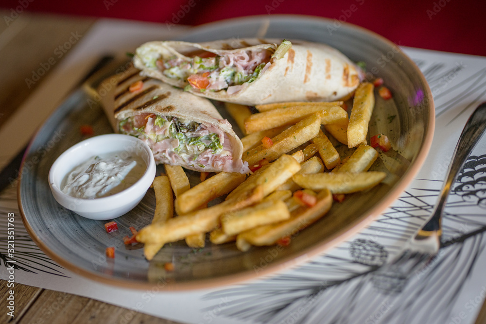 a tortilla filled with vegetables and chicken served with french fries a tortilla filled with vegetables and chicken served with french fries