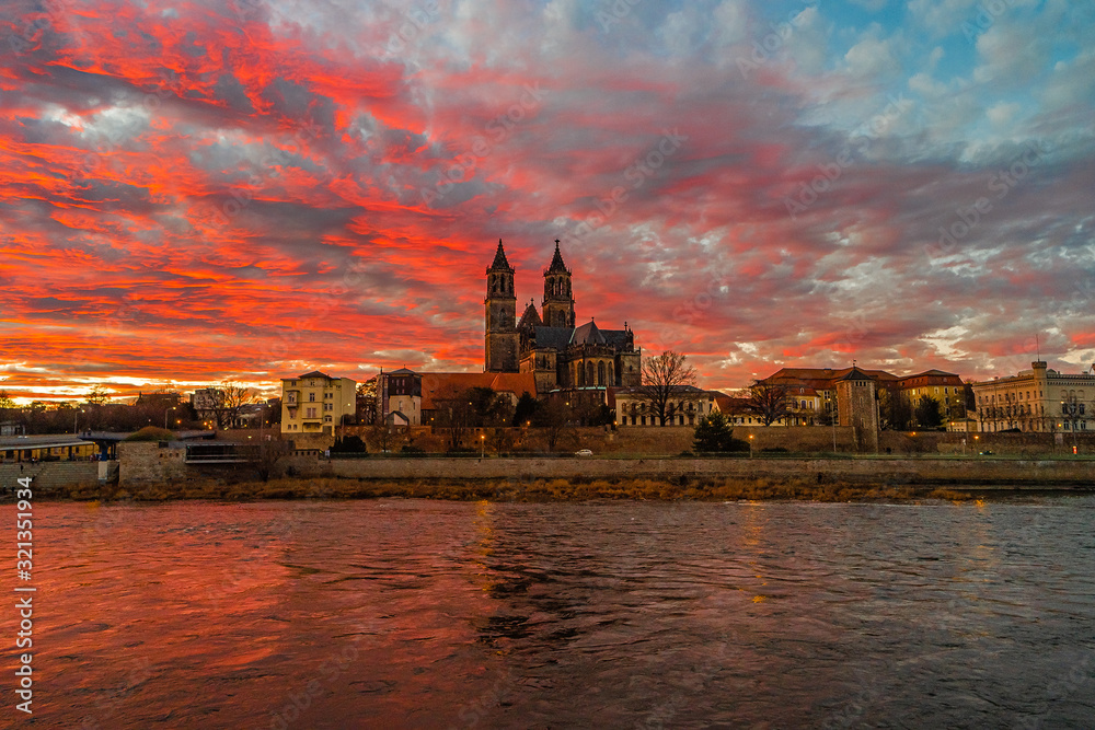 Panoramic view of beautiful bloody sunset in front of Cathedral of Magdeburg, downtown and river Elbe, Magdeburg, Germany, Winter, red cloudy sky