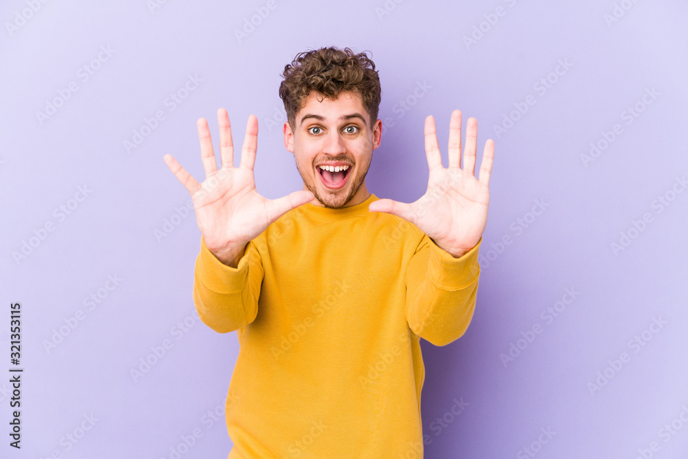 Fototapeta premium Young blond curly hair caucasian man isolated showing number ten with hands.