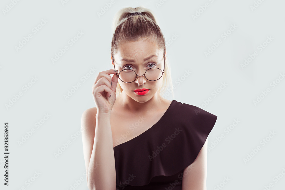 Skeptical suspicious young woman holding eye glasses down looking at you camera isolated on white light blue wall background