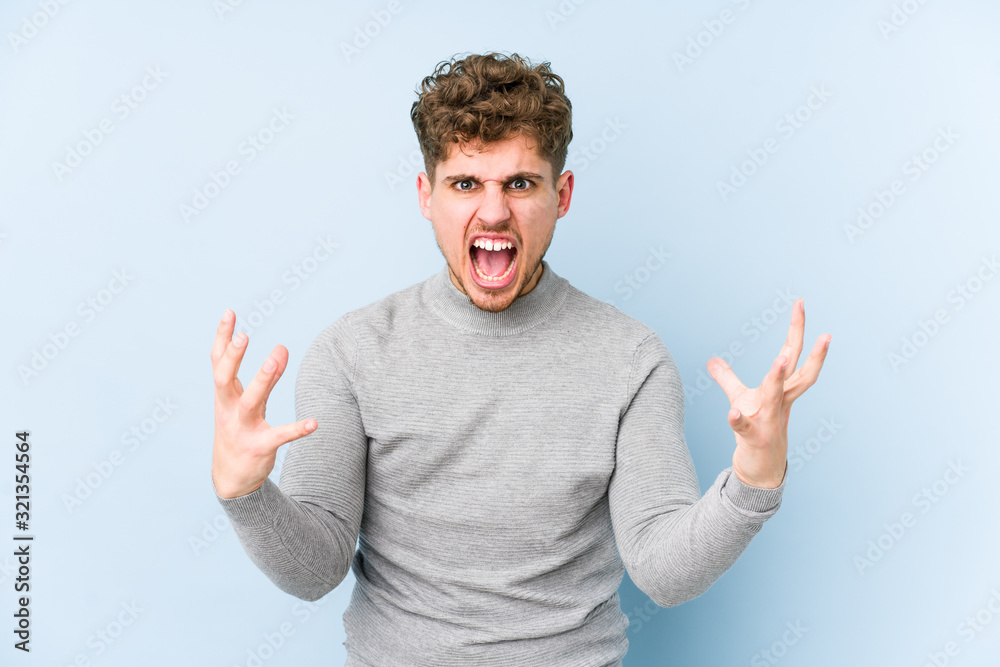 Young blond curly hair caucasian man isolated screaming with rage. Young blond curly hair caucasian man isolated screaming with rage.