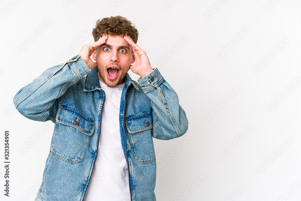 Young blond curly hair caucasian man isolated shouts loud, keeps eyes opened and hands tense. Young blond curly hair caucasian man isolated shouts loud, keeps eyes opened and hands tense.