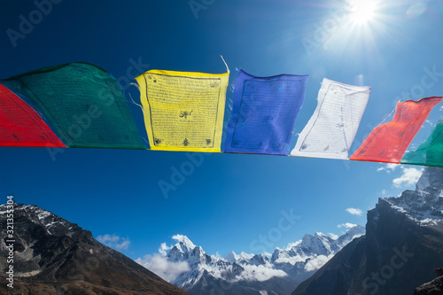 Holy buddhist praying multicolored flags with mantras flapping and waving on the  strong wind with valley view and Ama Dablam 6812m peak.Everest Base Camp trekking route near Dughla 4620m. photo