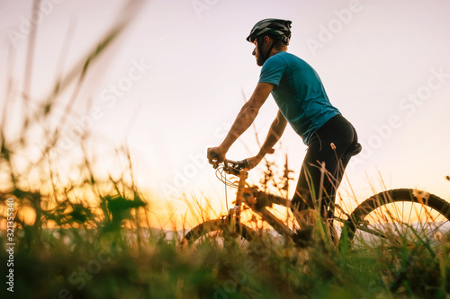 Foto Man biker man meets a sunset in top of hill over the city