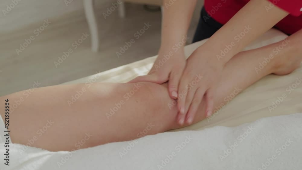 Female massage therapist massaging client's legs. Female massage therapist massaging client's legs.