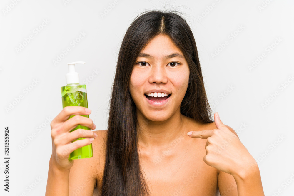 Young chinese woman holding a moisturizer with aloe vera isolated surprised pointing at himself, smiling broadly. Young chinese woman holding a moisturizer with aloe vera isolated surprised pointing at himself, smiling broadly.