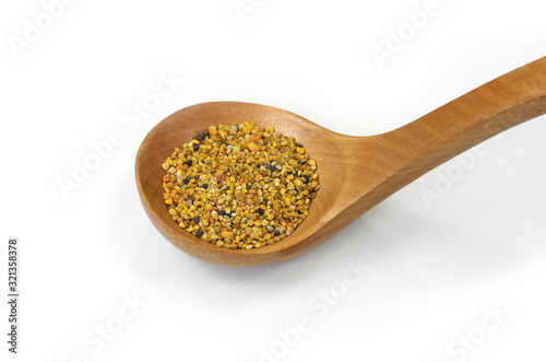 Pile of bee pollen in a wooden spoon isolated on white. © Sanja