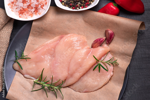 Raw chicken slices on a wooden table with raw vegetables and spices. Sottilissime. fresh, choped and sliced chicken meat. Cooking,raw sliced chicken breast.Top view. photo