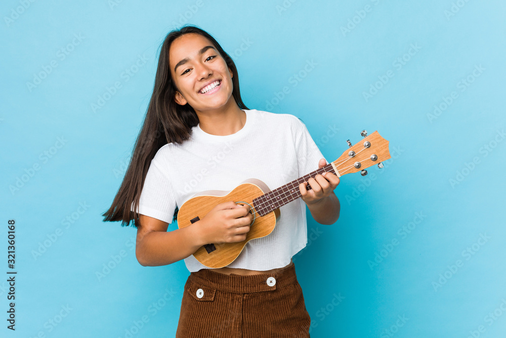 Young indian woman happy playing ukelele isolated Young indian woman happy playing ukelele isolated