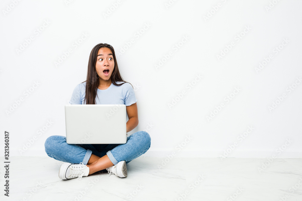 Young mixed race indian woman sitting working on laptop being shocked because of something she has seen.