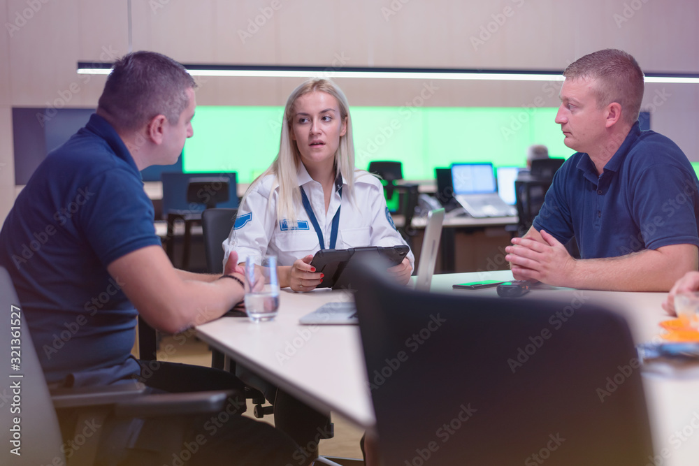 Obraz premium Security guard monitoring modern CCTV cameras in a surveillance room. Group of security guards sitting and monitoring.