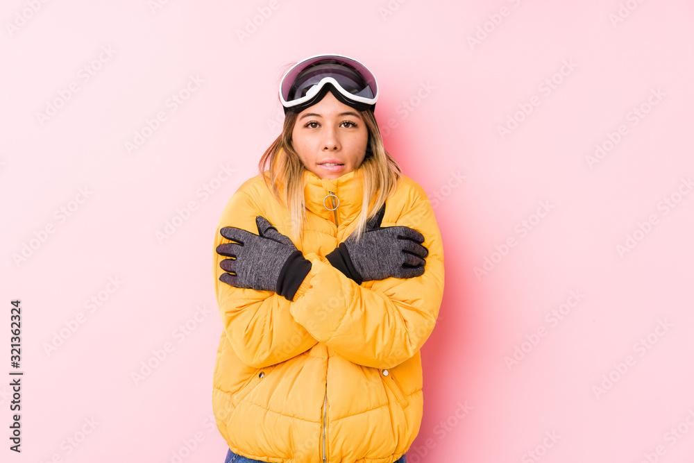 Young caucasian woman wearing a ski clothes in a pink background going cold due to low temperature or a sickness. Young caucasian woman wearing a ski clothes in a pink background going cold due to low temperature or a sickness.