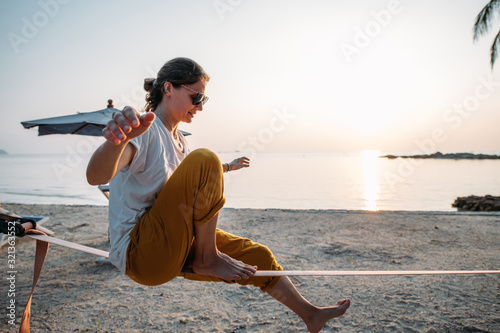 Girl goes on slackline at sunset on a tropical beach photo