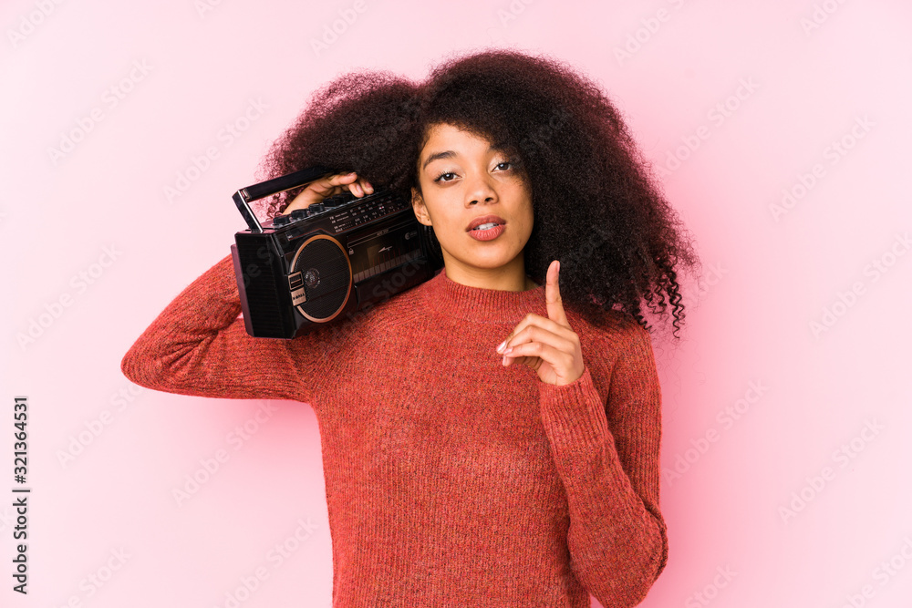 Obraz premium Young afro woman holding a cassete isolated having some great idea, concept of creativity.