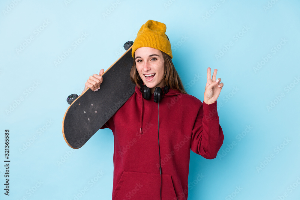 young skater caucasian woman isolated joyful and carefree showing a peace symbol with fingers. young skater caucasian woman isolated joyful and carefree showing a peace symbol with fingers.