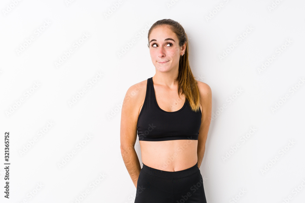 Young caucasian fitness woman posing in a white background confused, feels doubtful and unsure. Young caucasian fitness woman posing in a white background confused, feels doubtful and unsure.
