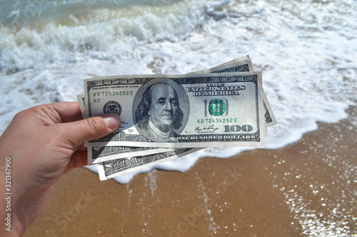 Girl holding a money bill of 300 dollars on background of sea waves photo