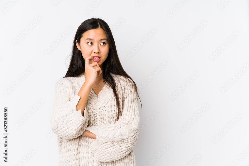 Young chinese woman isolated relaxed thinking about something looking at a copy space. Young chinese woman isolated relaxed thinking about something looking at a copy space.
