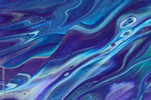 Rolling ocean waves of purple, bue, and metallic teal flow across the canvas in this abstract pour painting for backgrounds.