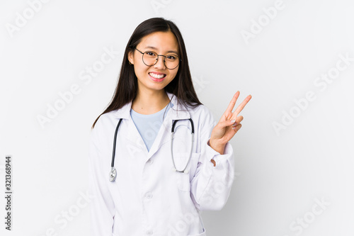 Young doctor chinese woman isolated joyful and carefree showing a peace symbol with fingers.