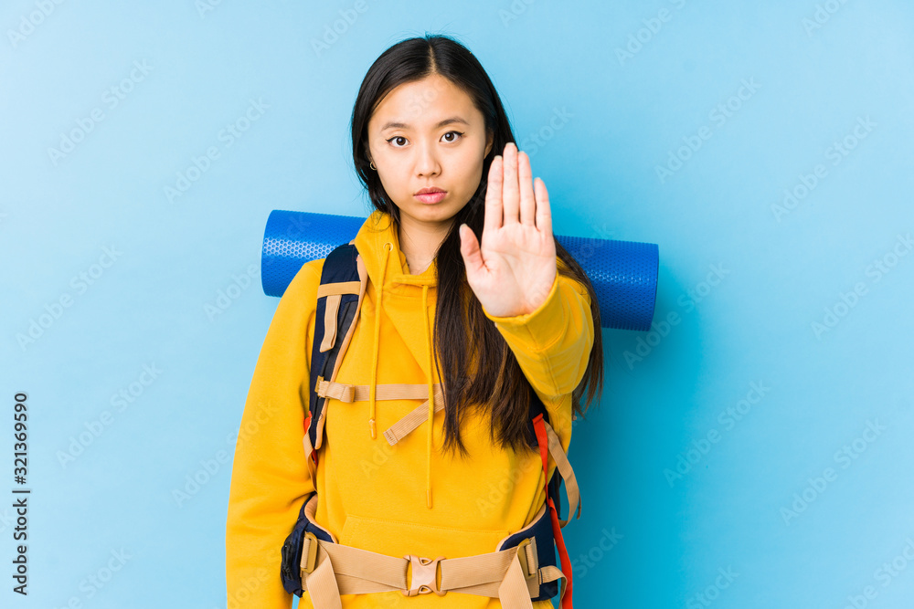 Young chinese backpacker woman isolated standing with outstretched hand showing stop sign, preventing you. Young chinese backpacker woman isolated standing with outstretched hand showing stop sign, preventing you.