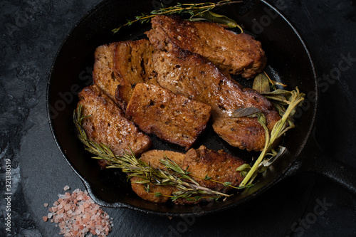 Roasted seitan in cast iron pan with various herbs and spices