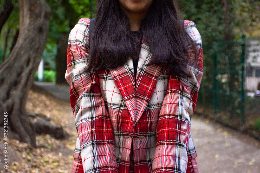 Young unrecognizable woman wearing a red checkered suit at the park Young unrecognizable woman wearing a red checkered suit at the park