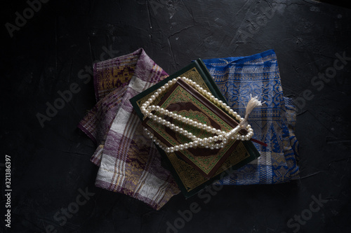 Faith in Islam, Holy book Islamic scripture al-Quran and rosary beads on dark background. Islamic holiday celebration Eid Mubarak or Ramadan Kareem concept. photo