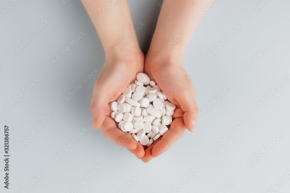 Obraz premium Round white pills on the palm of a female top view, overdose of pills. Copy space. Pharmacy and medical concept