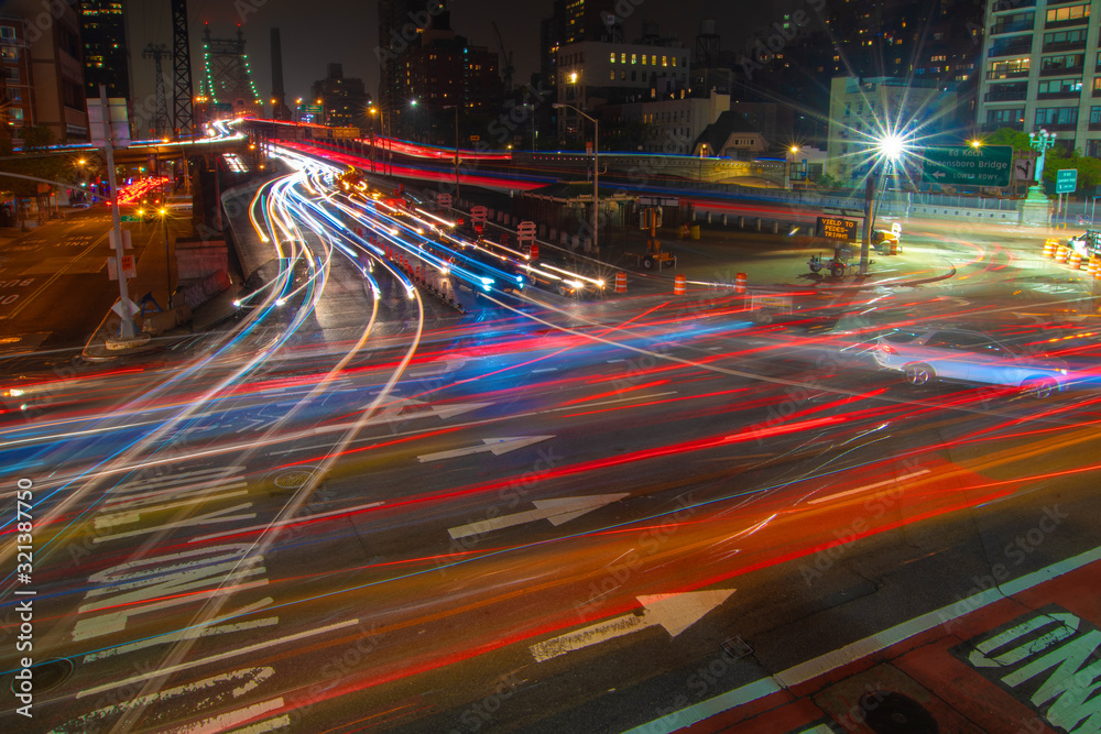 Obraz premium Busy traffic entering and exiting the Ed Koch Queensboro bridge at night leaving light streaks.