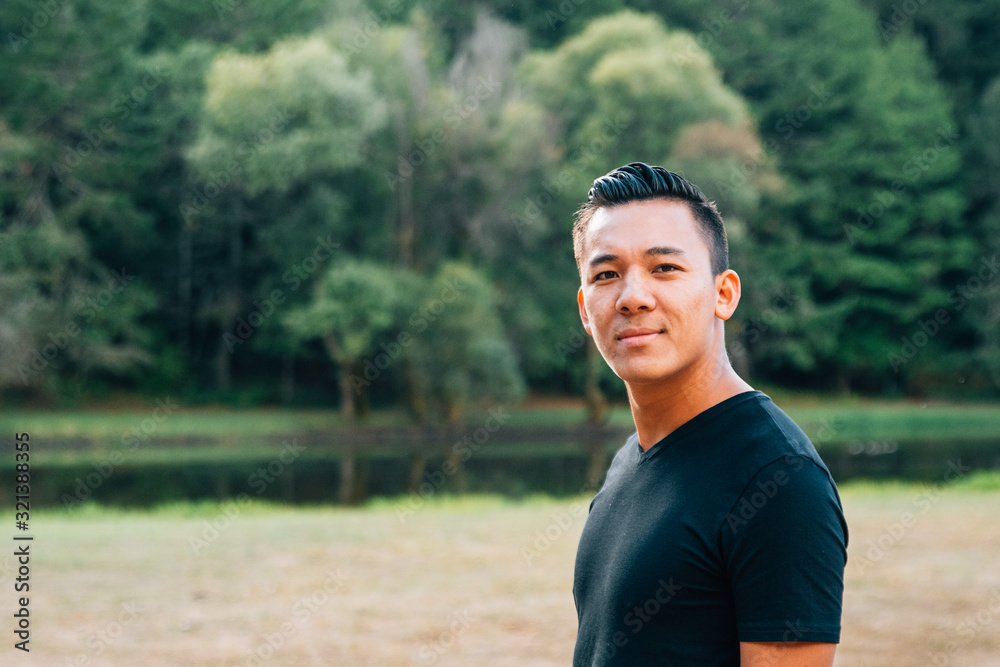 a portrait of young handsome Asian guy against green trees outside a portrait of young handsome Asian guy against green trees outside