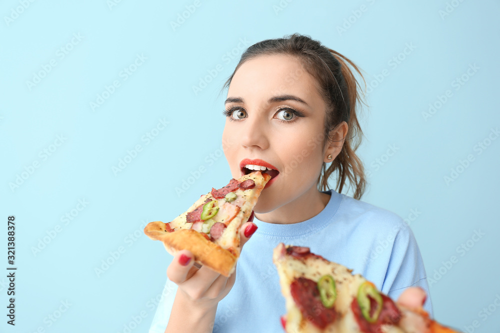 Portrait of beautiful young woman eating tasty pizza on color background Portrait of beautiful young woman eating tasty pizza on color background