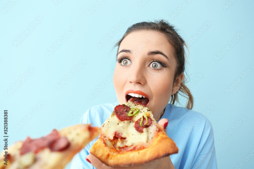 Portrait of surprised young woman eating tasty pizza on color background Portrait of surprised young woman eating tasty pizza on color background
