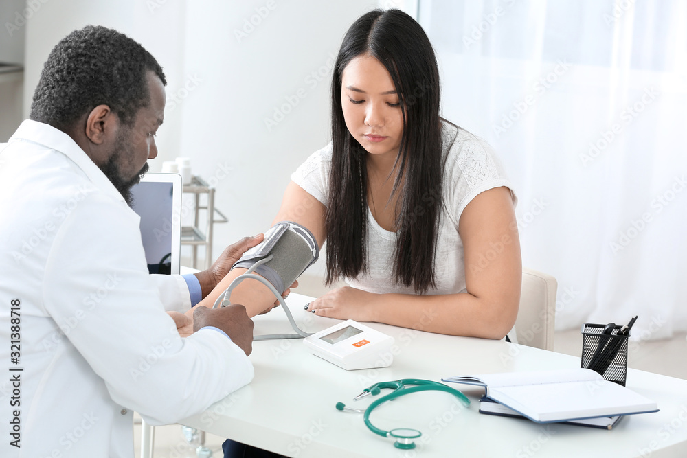 Fototapeta premium Male cardiologist examining female patient in clinic