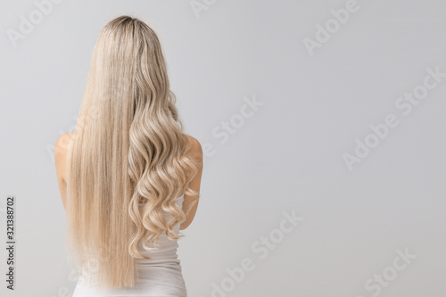 Beautiful young woman with curly and straight hair on light background photo
