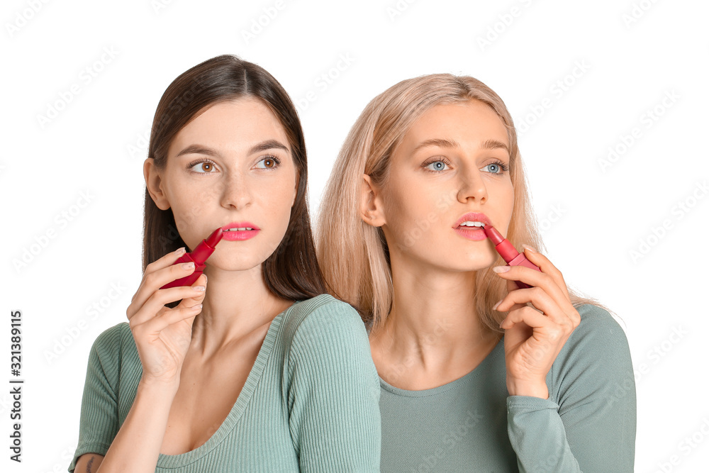 Beautiful young women applying makeup on white background Beautiful young women applying makeup on white background
