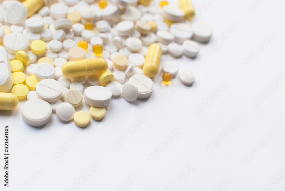 A bunch of yellow and white tablets and pills isolated on a white background close up. Medical pharmacy concept. Selective focus. A bunch of yellow and white tablets and pills isolated on a white background close up. Medical pharmacy concept. Selective focus.