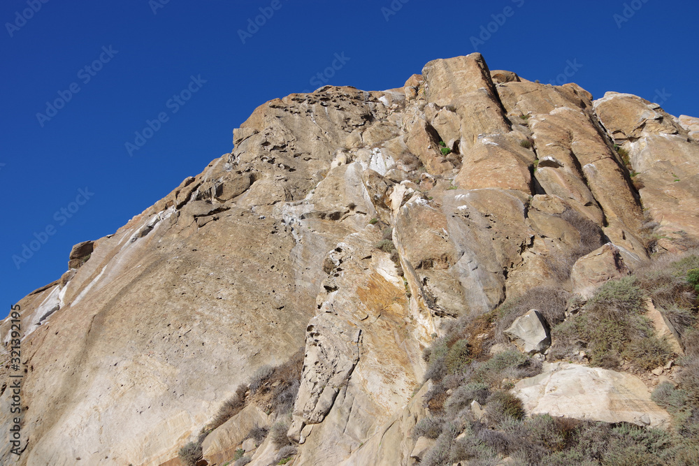 A steep rock in the California coastal mountain scape under deep blue sky