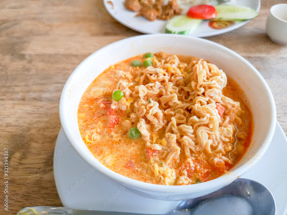 A white bowl of delicious instant noodle curry's tast cooked on wooden table, closeup image with copy space A white bowl of delicious instant noodle curry's tast cooked on wooden table, closeup image with copy space