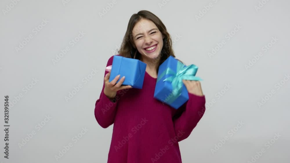 Fascinating excited brunette woman in pullover catching presents, holding gift boxes with expression of much joy and pleasure, celebrating birthday. indoor studio shot isolated on gray background Fascinating excited brunette woman in pullover catching presents, holding gift boxes with expression of much joy and pleasure, celebrating birthday. indoor studio shot isolated on gray background