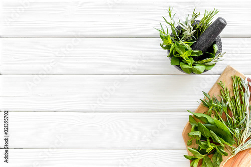 Make seasoning and condiments. Herbs in mortar on white wooden background top-down copy space