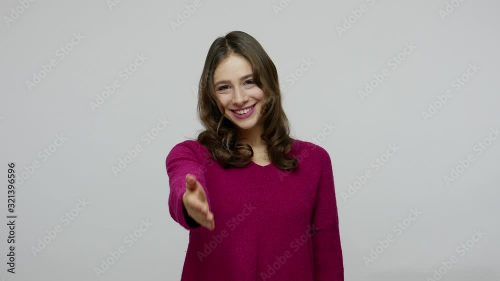 Welcome, happy to meet! Sociable friendly brunette woman in pullover offering hand to handshake and smiling to camera, getting to know new people. indoor studio shot isolated on gray background Welcome, happy to meet! Sociable friendly brunette woman in pullover offering hand to handshake and smiling to camera, getting to know new people. indoor studio shot isolated on gray background